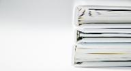 A stack of thick folders on a white surface