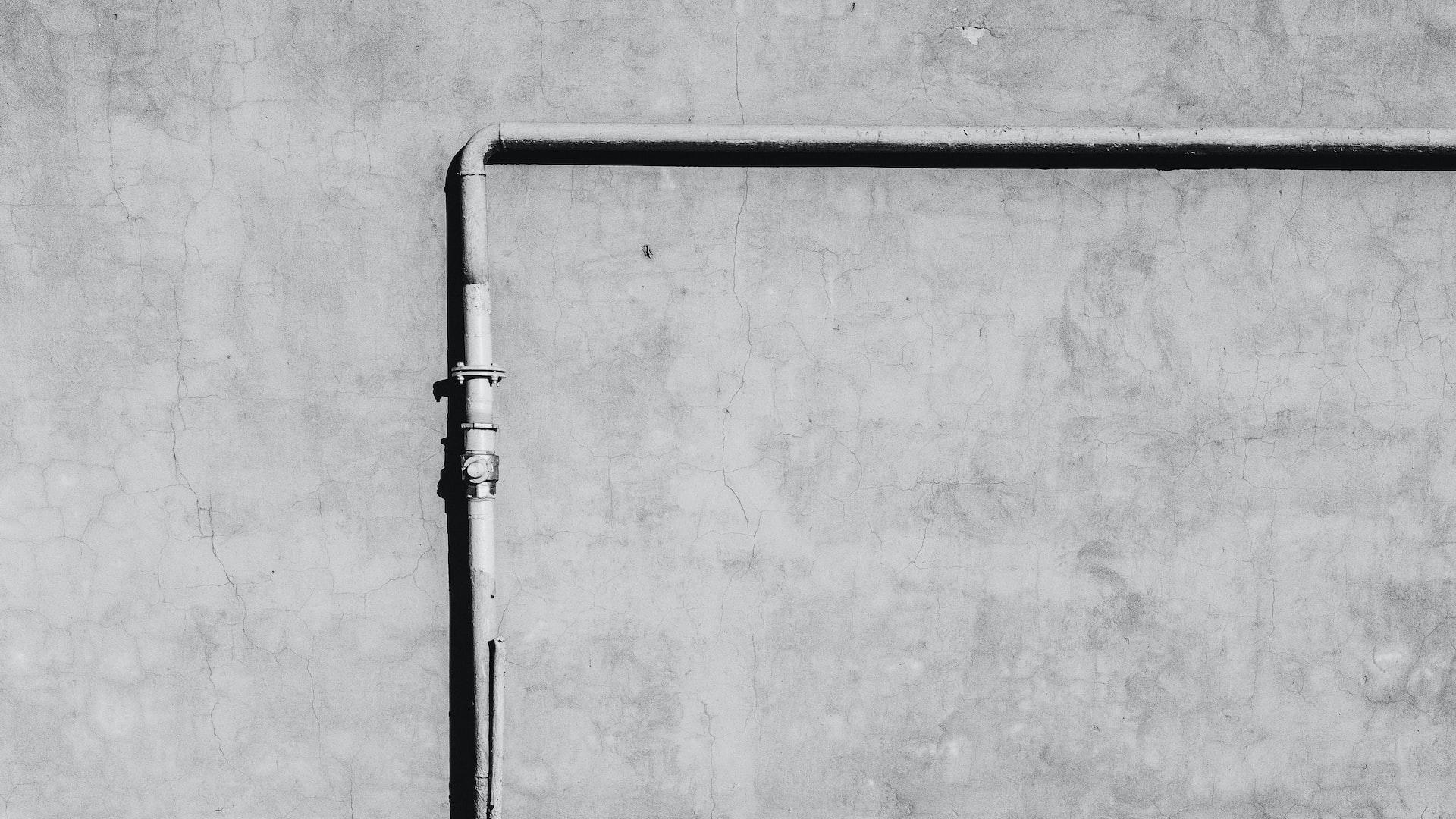 black metal rod leaning on white wall